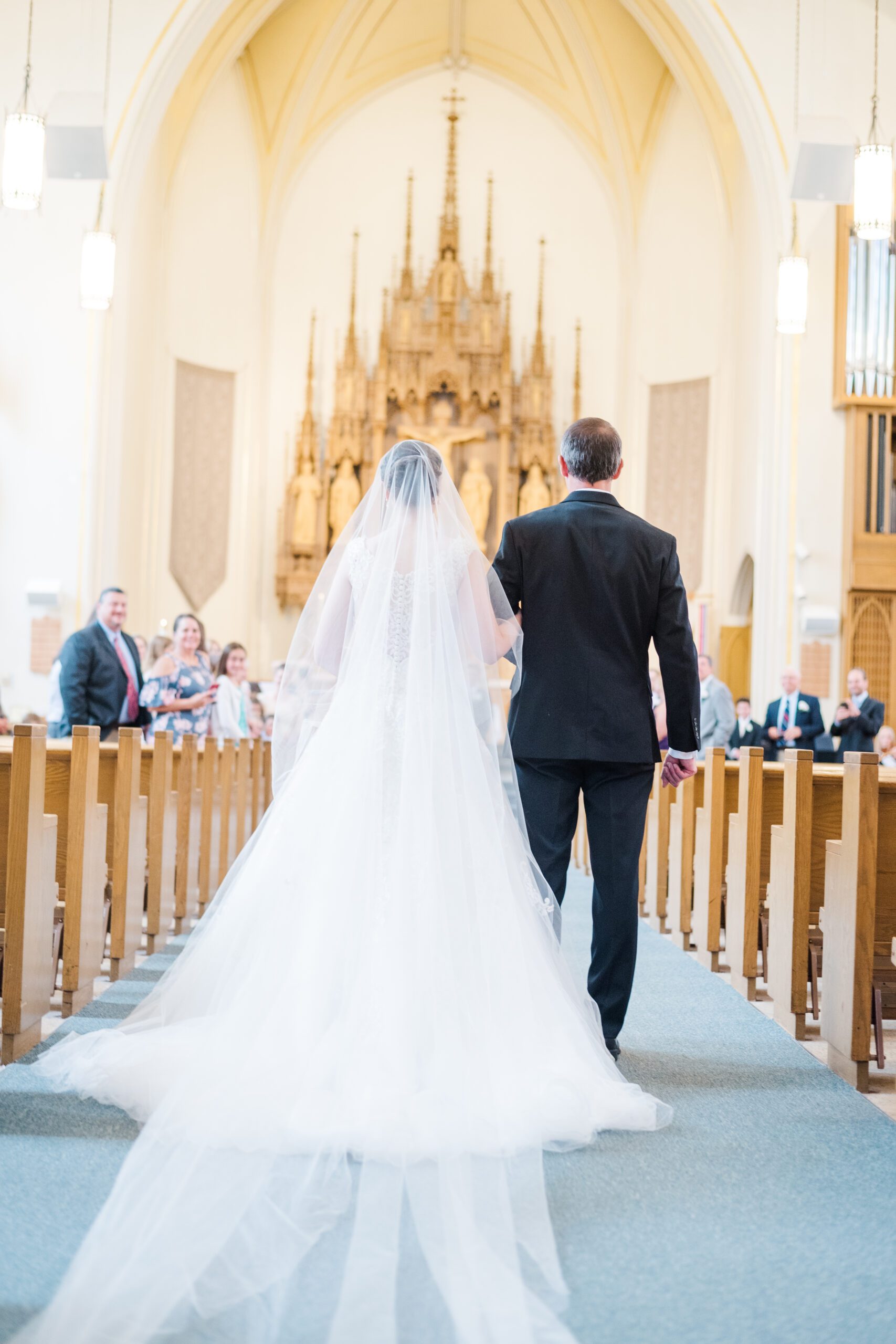 Bride is escorted down the aisle at church by her Father during a Catholic wedding ceremony.
