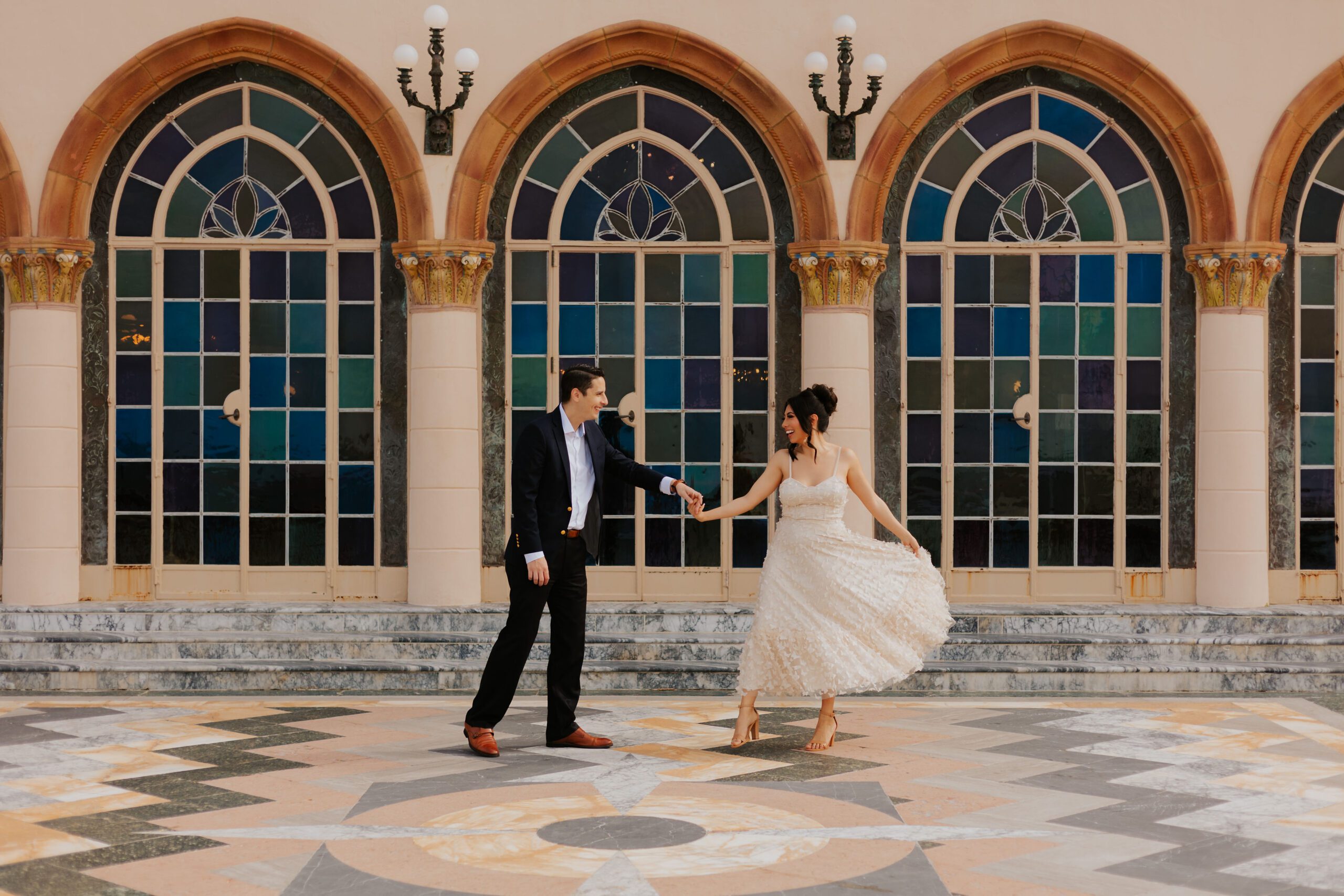 Bride and groom dance in front of stained glass window